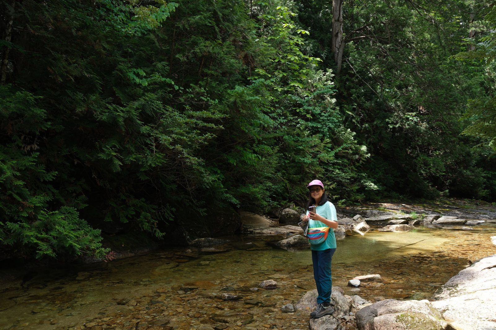 Standing on rocks beside a shallow, exceptionally clear mountain stream in the forest