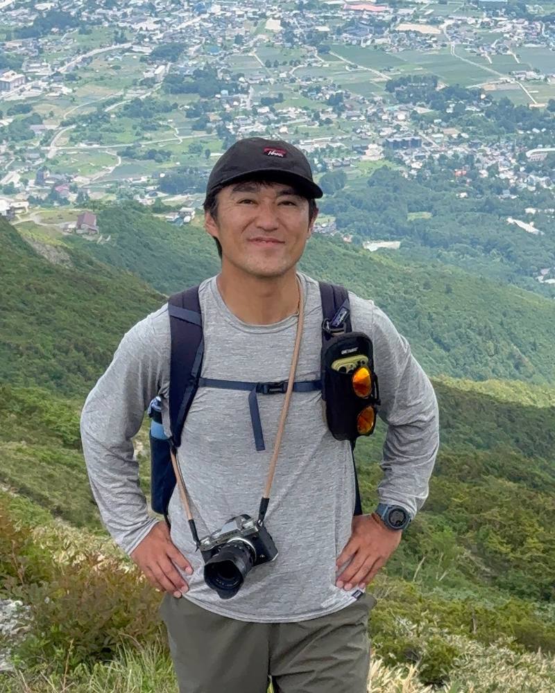 和田明宏在箱根山中，颈上挂着相机